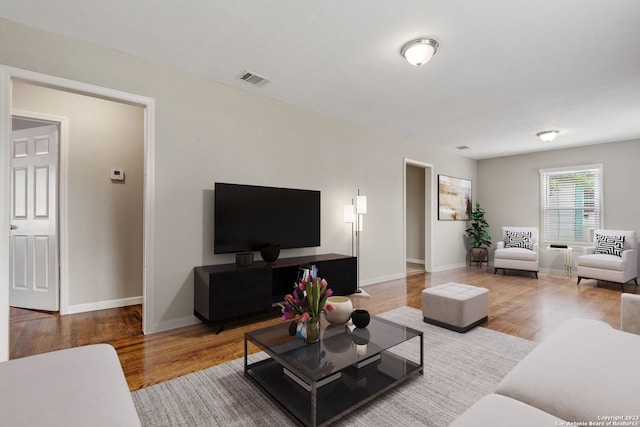 living area with wood finished floors, visible vents, and baseboards