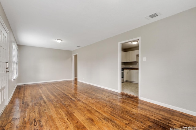 spare room with hardwood / wood-style floors, visible vents, and baseboards