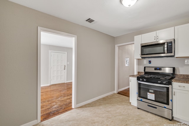 kitchen featuring appliances with stainless steel finishes, white cabinets, and light wood-type flooring