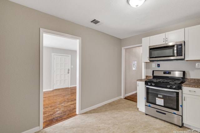 kitchen with appliances with stainless steel finishes, dark countertops, visible vents, and white cabinetry