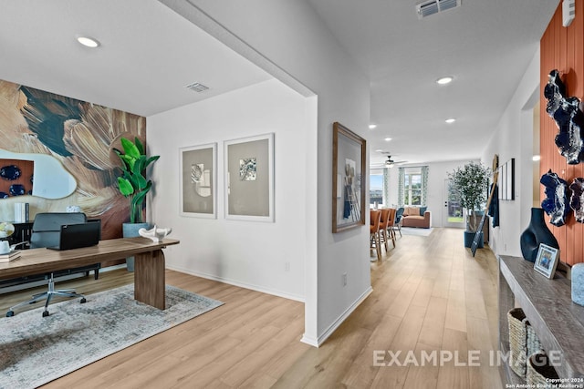 home office with light hardwood / wood-style floors and ceiling fan