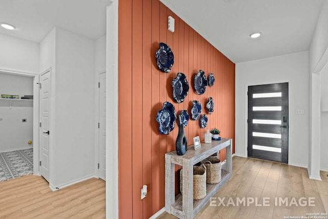 entrance foyer featuring light hardwood / wood-style flooring and wooden walls