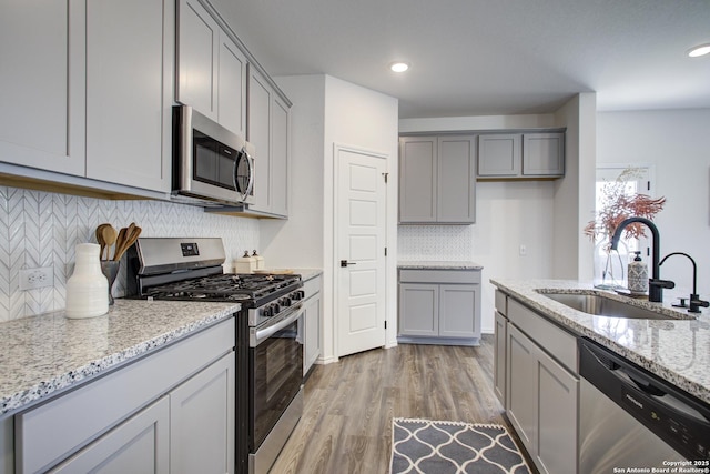 6934 Comanche Cave, San Antonio, TX 78233 - kitchen featuring stainless steel appliances, a sink, decorative backsplash, gray cabinets, and light stone countertops
