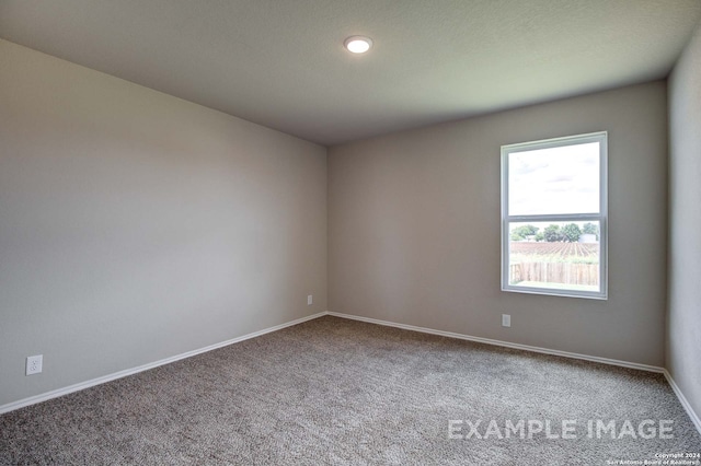 carpeted empty room featuring baseboards