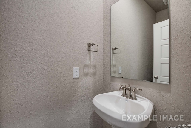 bathroom featuring a textured wall and a sink