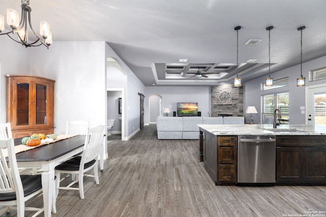 kitchen with decorative light fixtures, dishwasher, sink, dark brown cabinetry, and light stone counters