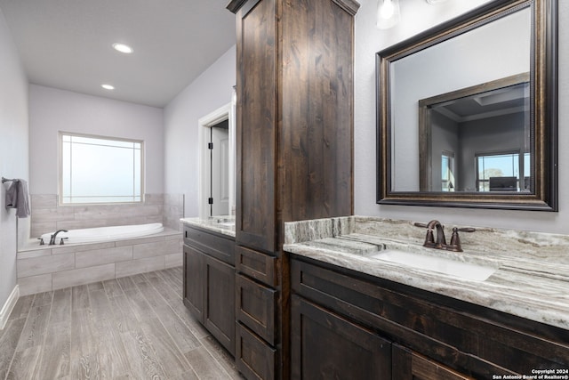 bathroom with vanity, wood-type flooring, and tiled bath