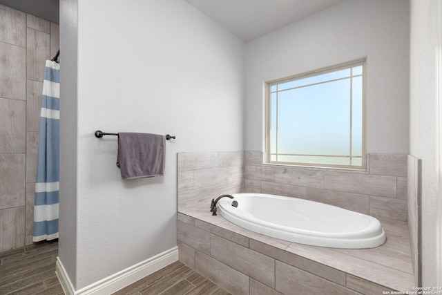 bathroom with independent shower and bath and wood-type flooring