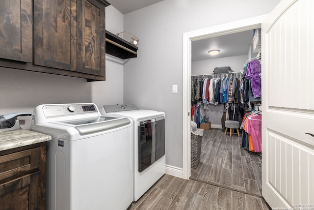 washroom with separate washer and dryer, wood-type flooring, and cabinets