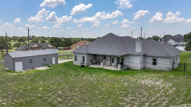 back of property featuring an outbuilding, a yard, a patio, and a garage