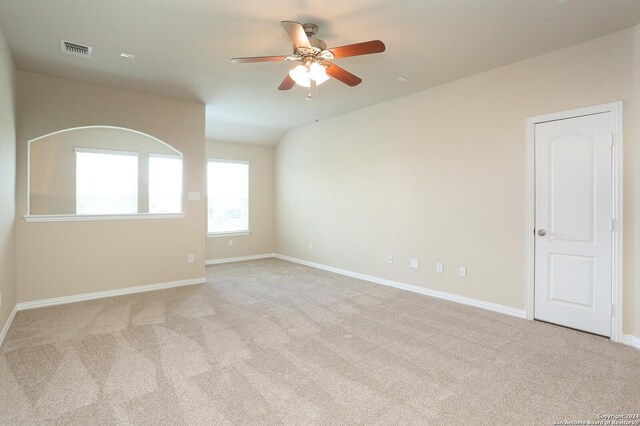 unfurnished room featuring light carpet, vaulted ceiling, and ceiling fan