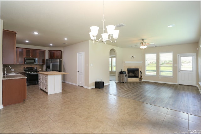 kitchen with light wood-type flooring, backsplash, a premium fireplace, black fridge with ice dispenser, and stove