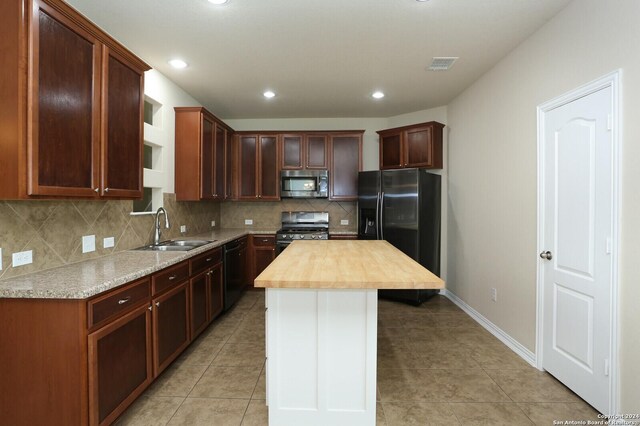 kitchen featuring black appliances, sink, butcher block counters, a kitchen island, and decorative backsplash