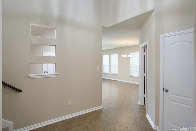 hall with an inviting chandelier and light tile patterned floors