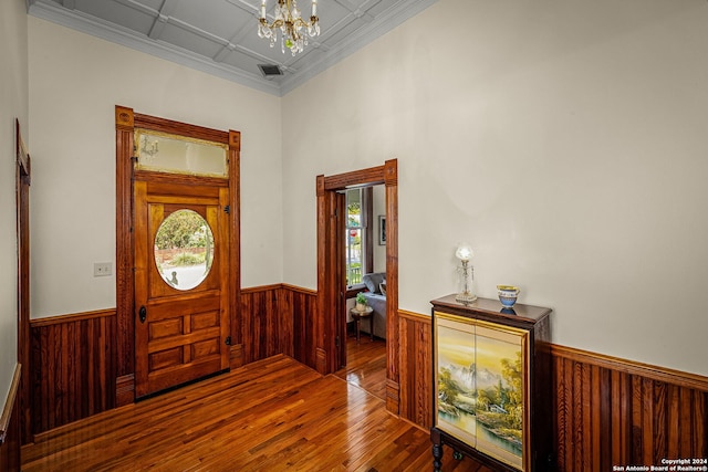 entrance foyer featuring wood-type flooring, a high ceiling, a chandelier, ornamental molding, and coffered ceiling