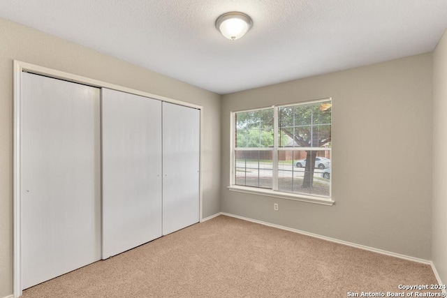 unfurnished bedroom featuring light carpet and a closet