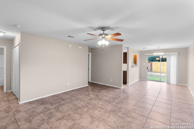 unfurnished living room with ceiling fan with notable chandelier and light tile patterned floors