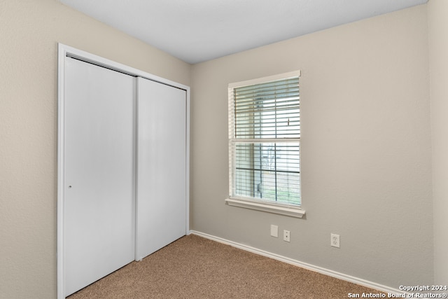 unfurnished bedroom with light carpet and a closet