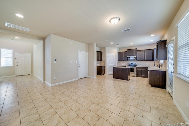 kitchen featuring sink, a center island, dark brown cabinets, stainless steel appliances, and backsplash