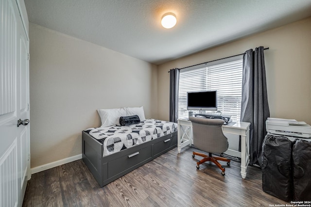 bedroom with dark hardwood / wood-style floors and a textured ceiling