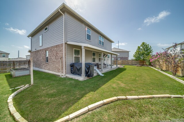 back of property with a yard and a patio