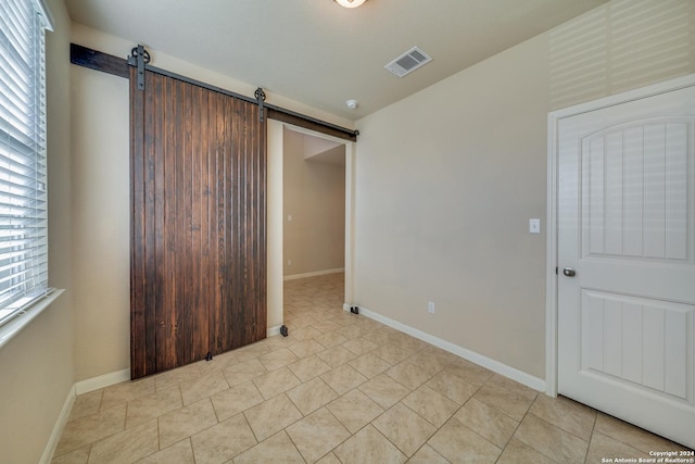 unfurnished bedroom featuring light tile patterned floors and a barn door