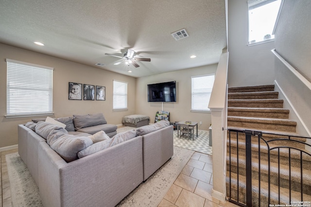 tiled living room with a textured ceiling, plenty of natural light, and ceiling fan