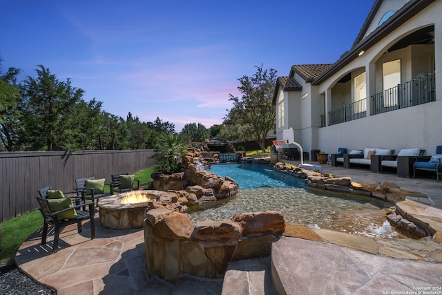 pool at dusk with a patio area, a fire pit, and pool water feature