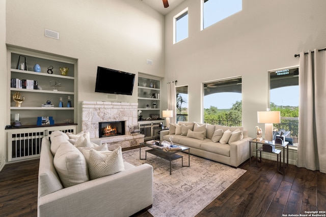 living room with dark hardwood / wood-style flooring, a fireplace, built in shelves, and a wealth of natural light