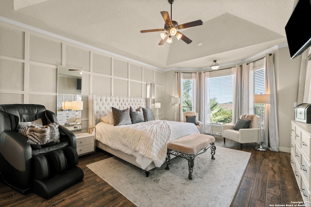 bedroom with ceiling fan, dark hardwood / wood-style floors, a raised ceiling, and multiple windows