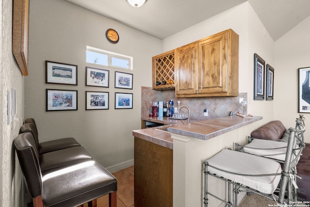 kitchen featuring tasteful backsplash, tile patterned floors, a breakfast bar, sink, and kitchen peninsula