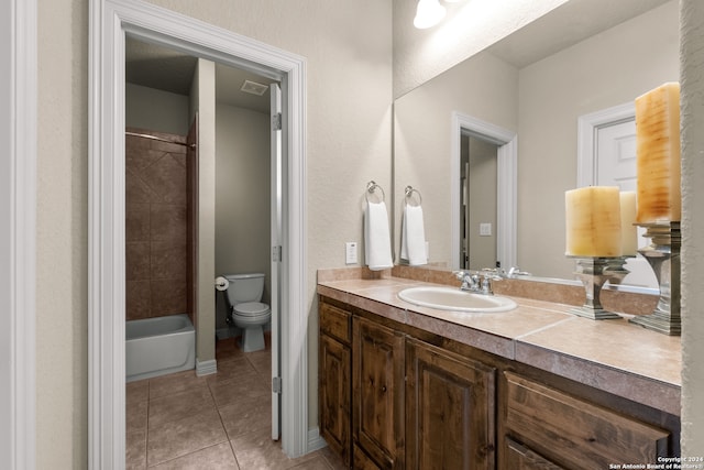 full bathroom with tile patterned flooring, vanity, tiled shower / bath combo, and toilet