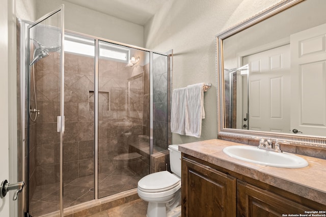 bathroom with tile patterned floors, toilet, vanity, and a shower with shower door