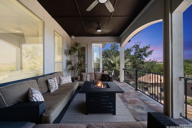 patio terrace at dusk featuring ceiling fan and an outdoor living space with a fire pit