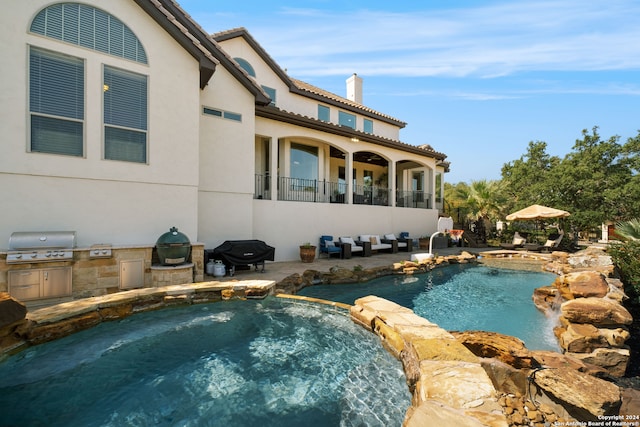 view of swimming pool with exterior kitchen, a patio, an in ground hot tub, pool water feature, and a grill