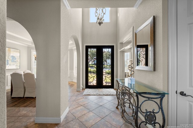 entrance foyer featuring ornamental molding, french doors, a notable chandelier, and light tile patterned floors