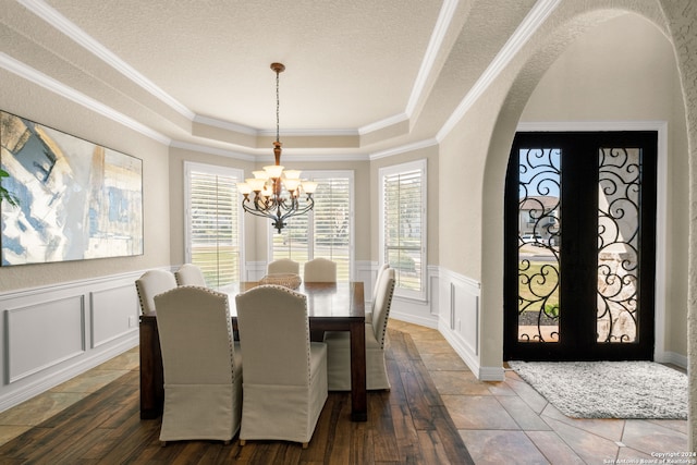 dining space with a tray ceiling, ornamental molding, french doors, a notable chandelier, and a textured ceiling