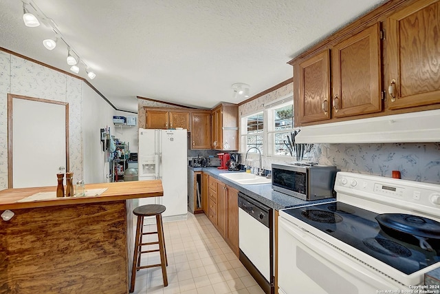 kitchen with a breakfast bar, sink, crown molding, a textured ceiling, and white appliances