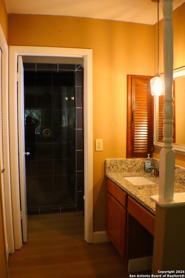 bathroom with vanity, a tile shower, and hardwood / wood-style floors