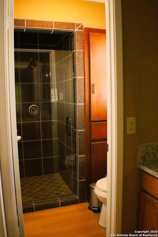 bathroom with vanity, toilet, wood-type flooring, and an enclosed shower