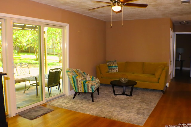 living room with a textured ceiling, hardwood / wood-style floors, and ceiling fan