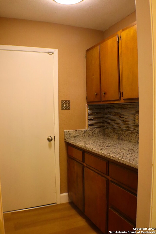 kitchen featuring light hardwood / wood-style flooring, decorative backsplash, and light stone counters