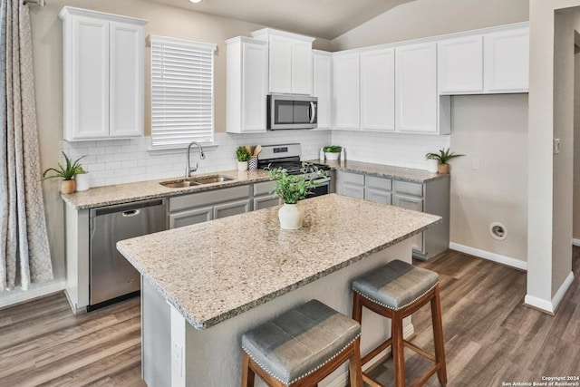 kitchen featuring a kitchen island, white cabinetry, sink, backsplash, and stainless steel appliances