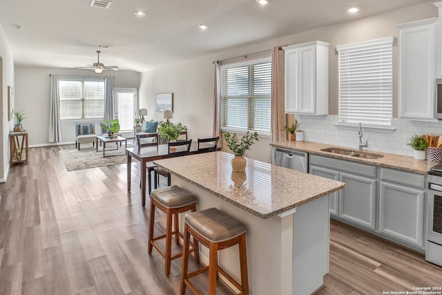 kitchen featuring light hardwood / wood-style flooring, a healthy amount of sunlight, a kitchen island, decorative backsplash, and ceiling fan