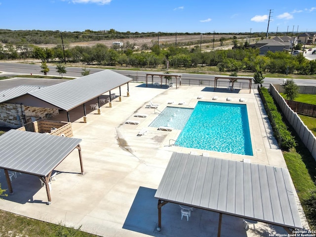 community pool with a patio area and fence