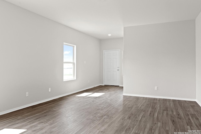 unfurnished room featuring baseboards and dark wood-style flooring