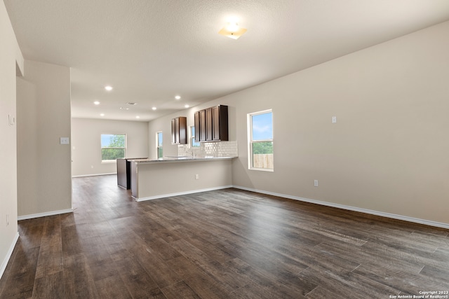 unfurnished living room with plenty of natural light, sink, and dark hardwood / wood-style floors