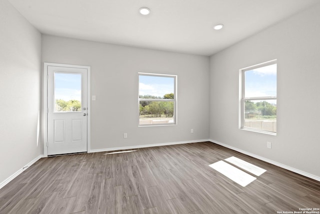 unfurnished room with recessed lighting, baseboards, a wealth of natural light, and wood finished floors