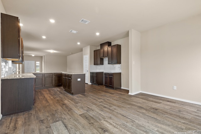 kitchen with a center island, backsplash, dark brown cabinetry, and hardwood / wood-style floors