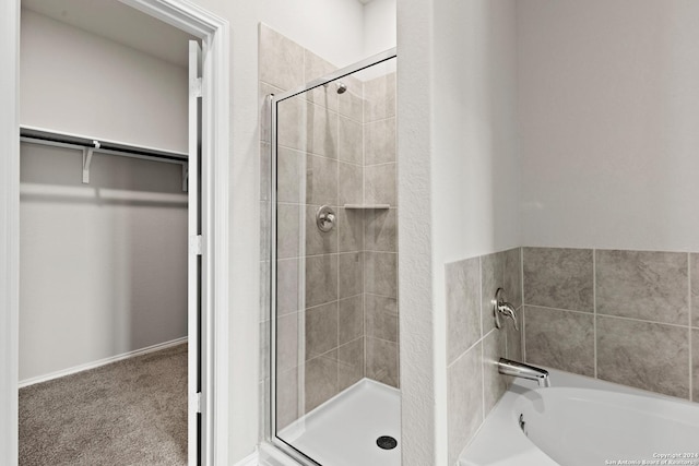 bathroom featuring a garden tub, a stall shower, and a walk in closet